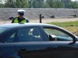Policjant Wydziału Ruchu Drogowego sprawdza stan trzeźwości kierującego pojazdem osobowym.